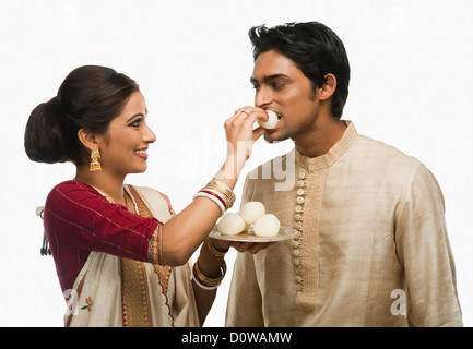 Bengali woman feeding a rasgulla to a man Stock Photo