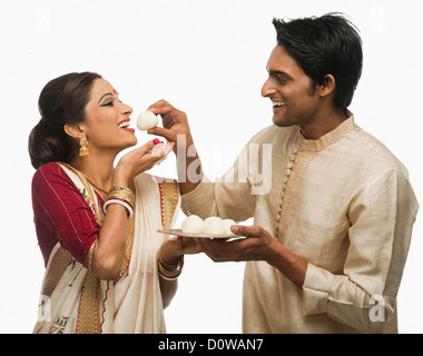 Bengali man feeding a rasgulla to his wife Stock Photo