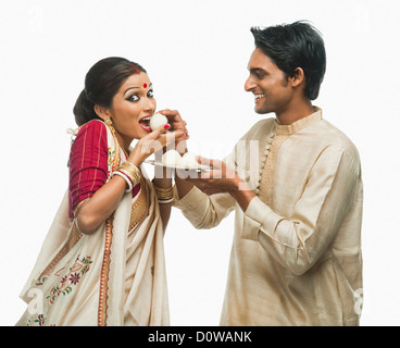 Bengali man feeding a rasgulla to his wife Stock Photo