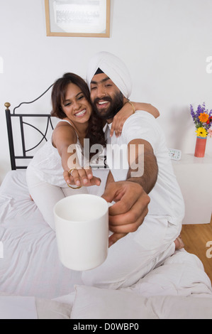 Woman reaching for a coffee cup held by her husband Stock Photo