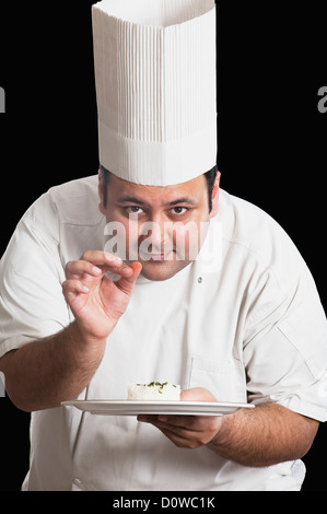 Chef sprinkling cumin seeds on a plate of rice Stock Photo