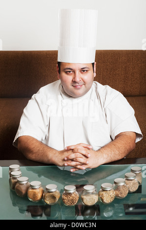 Chef smiling with assorted spices on a table, Gurgaon, Haryana, India Stock Photo