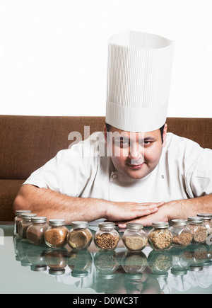 Chef smiling with assorted spices on a table, Gurgaon, Haryana, India Stock Photo