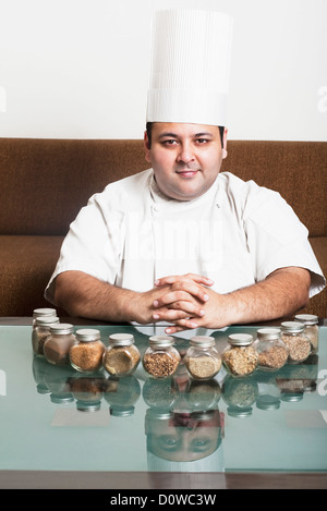 Chef smiling with assorted spices on a table, Gurgaon, Haryana, India Stock Photo