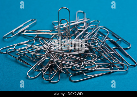 A pile of paper clips, on a blue background. Stock Photo