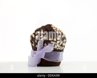 single chocolate muffin, decorated with white sugar stars, wrapped in purple ribbon, on white backround Stock Photo