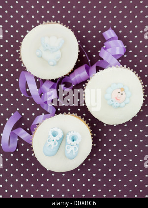 three muffins for newborns with holiday decorations purple ribbon on purple background with dots  Stock Photo