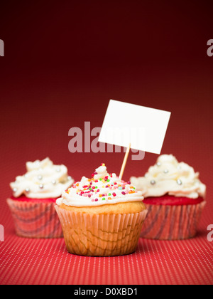 muffins with colorful candy on the table red with white dots and blank sign board gradient red background Stock Photo