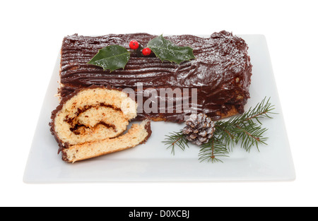 Chocolate yule log on a plate decorated with holly and seasonal foliage isolated against white Stock Photo