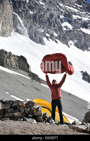 Woman shakes her sleeping bag at Camp One on Aconcagua in the Andes Mountains, Mendoza Province, Argentina Stock Photo