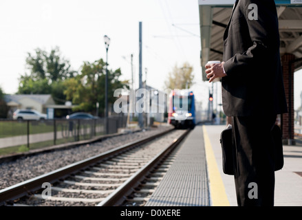 Businessman waiting for approaching train Stock Photo