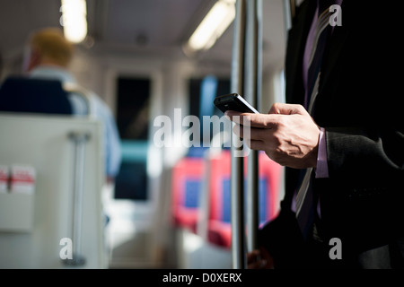 Businessman on train using smartphone Stock Photo