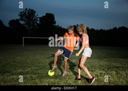 Friends playing soccer at night Stock Photo