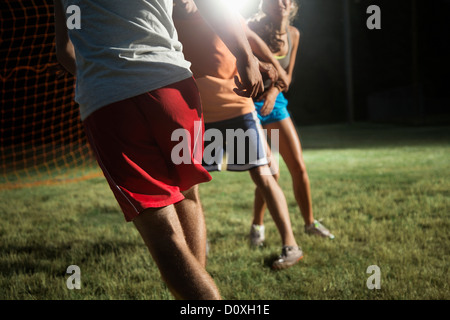 Friends playing soccer at night Stock Photo