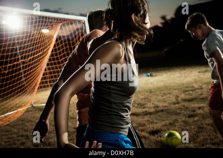 Friends playing soccer at night Stock Photo