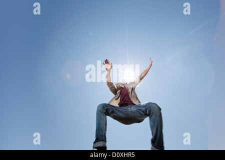 Young man jumping against blue sky, low angle Stock Photo
