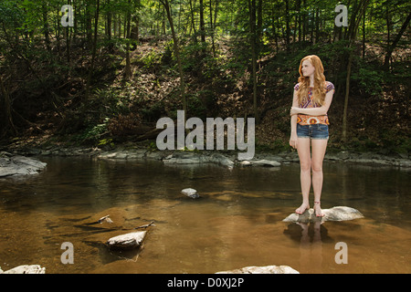 Teenage girl standing on rock in river Stock Photo