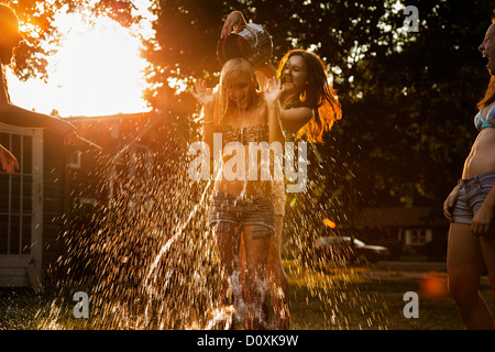 Girl pouring bucket of water over friend's head Stock Photo