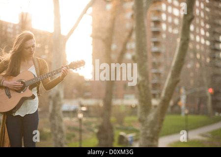 Young woman playing guitar in the park Stock Photo