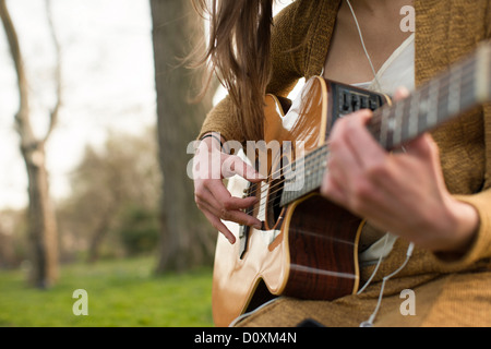 Young woman playing guitar outdoors Stock Photo