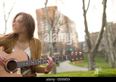 Young woman playing guitar outdoors Stock Photo