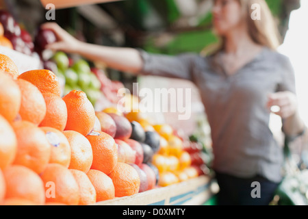 Young woman picking out fruit from stall Stock Photo