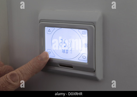 Person adjusting digital thermostat Stock Photo