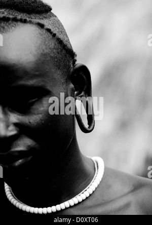 Black And White Partial Portrait Of A Surma Tribe Warrior With Enlarged Ear, Omo Valley, Ethiopia Stock Photo