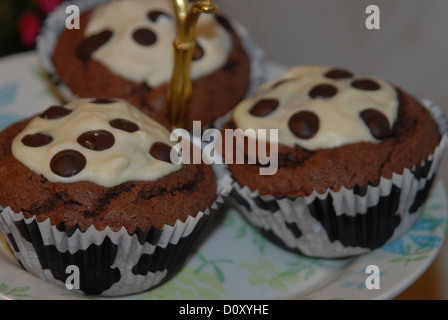 Chocolate cupcakes on a cake stand, afternoon tea. Cupcake liners with cow pattern. Stock Photo