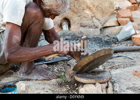 Old rural indian village man metalworking at a small outside furnace. Andhra Pradesh India Stock Photo