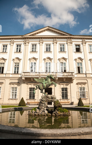 Front of the baroque Mirabell Palace in Salzburg with a bronze statue of Pegasus in the reflective pond and a blue cloudy sky. Stock Photo