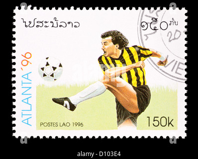 Postage stamp from Laos depicting depicting a soccer player kicking a soccer balls, issued for the 1996 Summer Olympic  games. Stock Photo