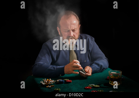 A cigar smoking mature male shuffles his cards Stock Photo