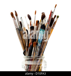 Assorted dirty old painting brushes in a glass flask. Isolated on white Stock Photo