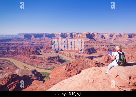 Hiker reading map at Gooseneck Bend Colorado River  Dead Horse Point State Park Overlook  Utah USA United States of America Stock Photo