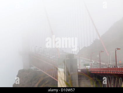 The San Francisco Golden Gate Bridge covered in fog and pedestrians walking across the bridge and cars driving across. Stock Photo