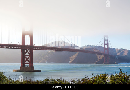 The San Francisco Golden Gate Bridge covered in fog and pedestrians walking across the bridge and cars driving across. Stock Photo