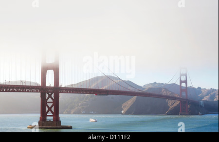 The San Francisco Golden Gate Bridge covered in fog and pedestrians walking across the bridge and cars driving across. Stock Photo