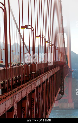 The San Francisco Golden Gate Bridge covered in fog and pedestrians walking across the bridge and cars driving across. Stock Photo