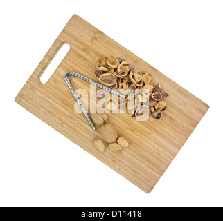 A group of shelled nuts with whole walnuts and almonds and nutcracker on a wood cutting board. Stock Photo