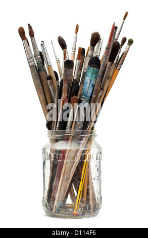 Assorted dirty old painting brushes in a glass flask. Stock Photo