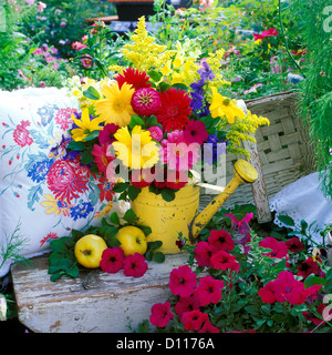 BOUQUET OF PINK  YELLOW  PURPLE FLOWERS IN YELLOW WATERING CAN IN GARDEN Stock Photo