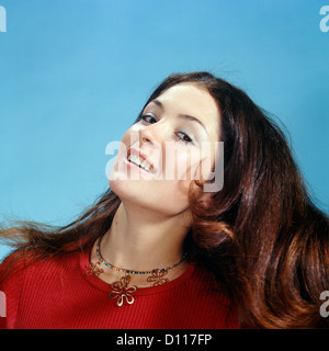 1960s 1970s PORTRAIT OF SMILING WOMAN TOSSING BACK HER LONG BROWN HAIR WEARING RED TOP LOOKING AT CAMERA Stock Photo