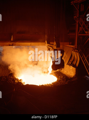 INTERIOR OF STEEL MILL WITH MOLTEN STEEL BEING POURED FROM CRUCIBLE Stock Photo