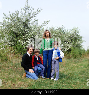 1970s PORTRAIT FAMILY STANDING IN ORCHARD MOTHER FATHER TWO BOYS Stock Photo