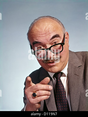 1960s BALDING MAN LOOKING AT CAMERA OVER TOP OF EYEGLASSES POINTING FINGER Stock Photo