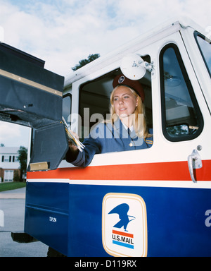 1970s FEMALE MAIL CARRIER IN U.S. MAIL TRUCK DELIVERING MAIL TO HOME MAILBOX Stock Photo