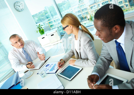 Portrait of senior boss and his employees discussing new project at meeting Stock Photo