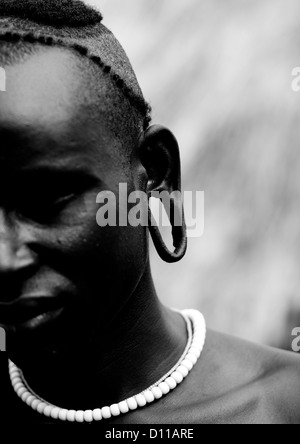 Black And White Partial Portrait Of A Surma Tribe Warrior With Enlarged Ear, Omo Valley, Ethiopia Stock Photo