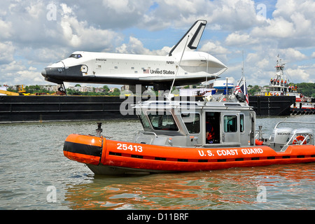 A Coast Guard boat crew from Station New York enforces a safety zone around a barge carrying the retired Space Shuttle Enterprise while it transits through New York Harbor to the Intrepid Sea, Air and Space Museum June 6, 2012. Stock Photo